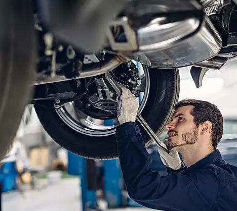 Mechanic working on car undercarriage checking suspension