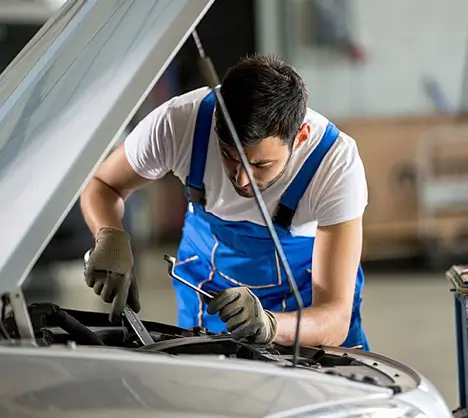 Mechanic working on car engine to carry out regular/logbook service.